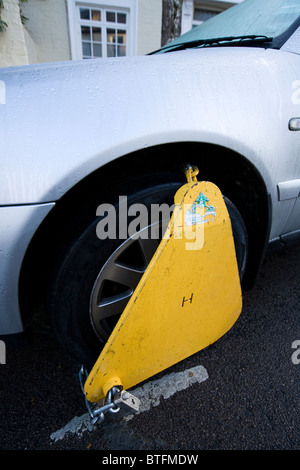 A wheel clamp fitted by the DVLA to a car whose keeper has not paid vehicle tax / has valid TAX disc. UK. Stock Photo