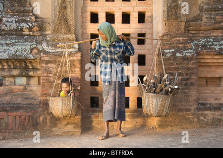 Burmese woman carrying two baskets, one with her boy, Bagan (Pagan), Myanmar (Burma) Stock Photo