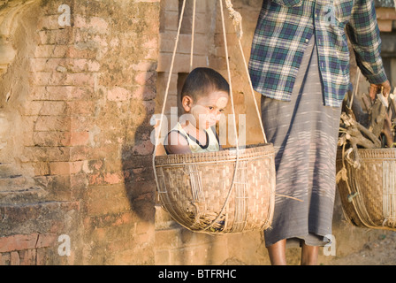 Burmese woman carrying two baskets, one with her boy, Bagan (Pagan), Myanmar (Burma) Stock Photo