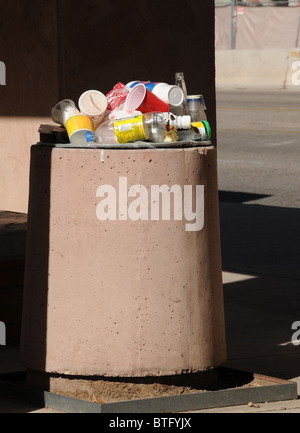 A trash receptacle overflows with some items that are recyclable. Stock Photo