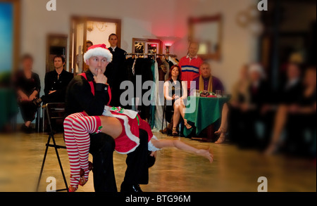 This young Caucasian couple are performing a ballroom Christmas dance to "Santa Baby" where the woman in a short skirt. Stock Photo
