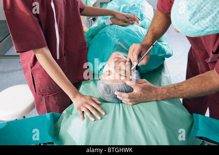 Surgeon marking incision lines on face in operating room Stock Photo