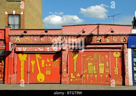 DIY Store with shutters down showing keys and hardware painted on the front, Blackstock Road Finsbury Park N4 London England UK Stock Photo