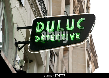 retro green neon sign for detective agency mounted on 19th century building facade Rue du Louvre Paris Stock Photo