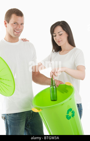 Couple throwing glass bottle in the recycling bin Stock Photo