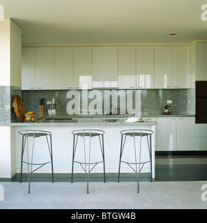 Black metal stools at breakfast bar in modern white kitchen with granite splash-back Stock Photo