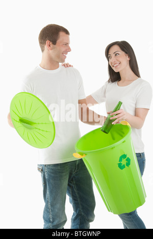 Couple throwing glass bottle in the recycling bin Stock Photo