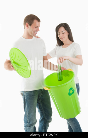 Couple throwing glass bottle in the recycling bin Stock Photo