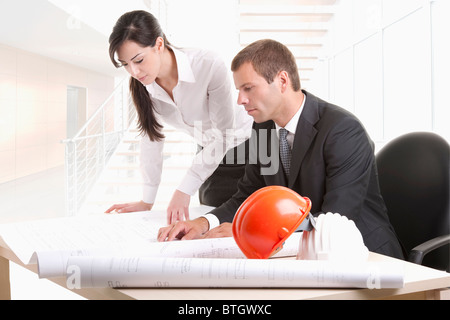 Man and woman looking over plans at desk Stock Photo