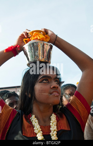 Hindu devotee with pieced cheeks carrying a lota with water during Thaipusam Festival at Batu Caves in Kuala Lumpur, Malaysia Stock Photo