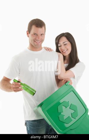 Couple throwing glass bottle in the recycling bin Stock Photo