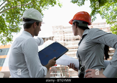 Man and woman with hardhats at construction site Stock Photo