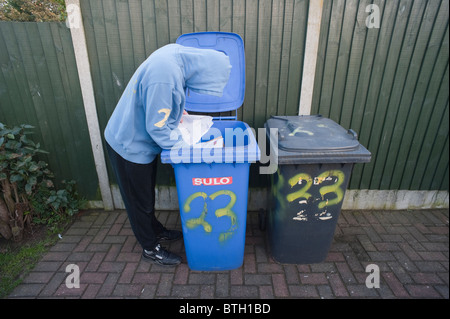 A MODEL RELEASED picture of a hooded male looking through someone's bins to find bank details etc. for identity fraud in the Uk Stock Photo