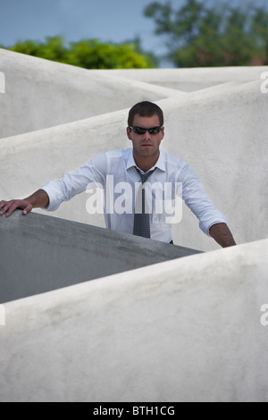 Man with tie and sunglasses standing behind wall Stock Photo