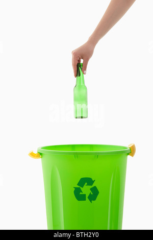 Young woman's arm throwing glass bottle in the recycling bin Stock Photo