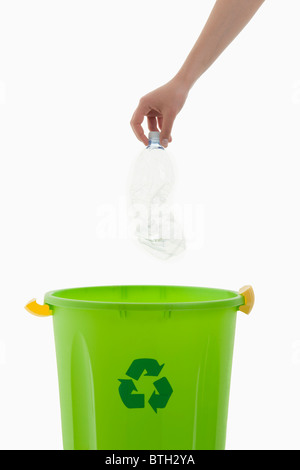 Young woman's arm throwing plastic bottle in the recycling bin Stock Photo