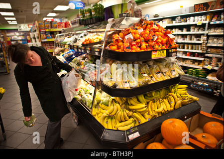 A woman shopper looking at fresh fruit and vegetables in Spar convenience store UK Stock Photo