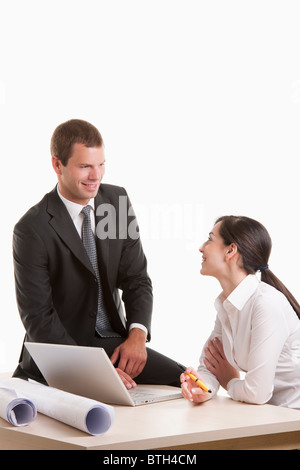 Man and woman with plans and laptop at desk Stock Photo