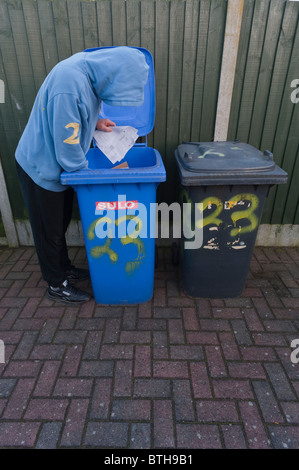 A MODEL RELEASED picture of a hooded male looking through someone's bins to find bank details etc. for identity fraud in the Uk Stock Photo