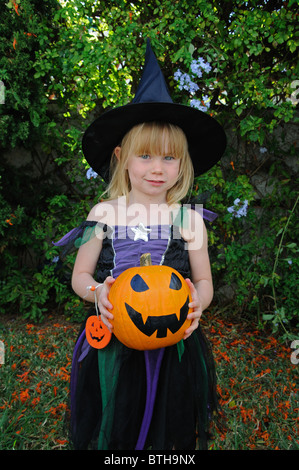 Young girl dressed as a witch (holding a pumpkin) for Halloween, Mijas Costa, Costa del Sol, Malaga Province, Andalucia, Spain. Stock Photo