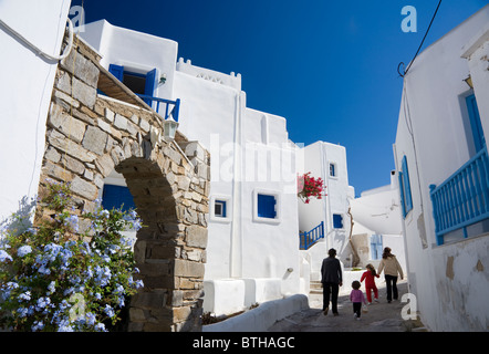 Two women walking with two children in a typical narrow street of Naoussa, on the Greek Cyclade island of Paros. Stock Photo