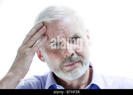 portrait on isolated withe background of a handsome expressive senior holding his head in hand headache memory loss migraine Stock Photo