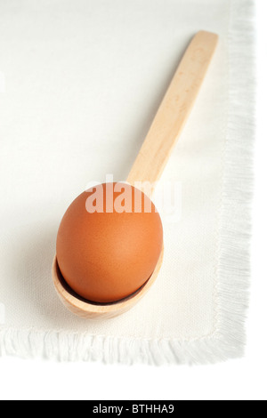 Brown egg in a wooden spoon on a white napkin Stock Photo