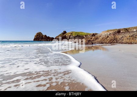 White surf bubbles on the sands of Kynance Cove beach, The Lizard, Cornwall Stock Photo