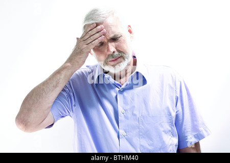 portrait on isolated withe background of a handsome expressive senior holding his head in hand headache memory loss migraine Stock Photo