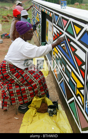 Ndebele Women Painting Traditional Designs on Walls, Ndelebe Cultural Village, Botshabelo, South Africa. Stock Photo