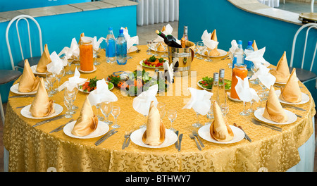 laid banquet round restaurant table with golden tablecloth Stock Photo