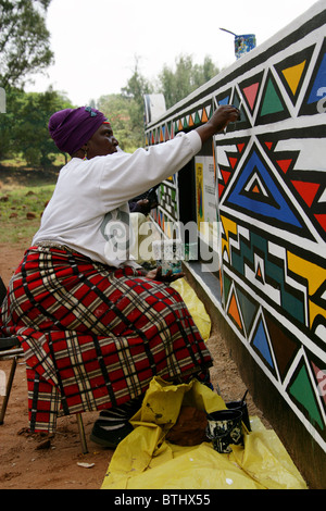 Ndebele Women Painting Traditional Designs on Walls, Ndelebe Cultural Village, Botshabelo, South Africa. Stock Photo