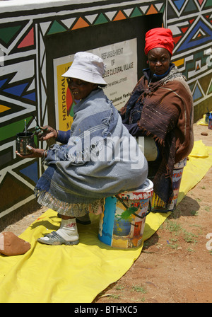 Ndebele Women Painting Traditional Designs on Walls, Ndelebe Cultural Village, Botshabelo, South Africa. Stock Photo