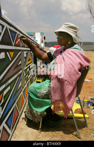 Ndebele Women Painting Traditional Designs on Walls, Ndelebe Cultural Village, Botshabelo, South Africa. Stock Photo