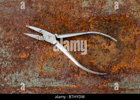 Pair of Needle-Nose or Long-Nose Pliers on a rusty background Stock Photo