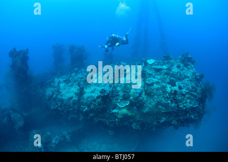 A diver hovers over the fallen smokestack on a WWII wreck, the Iro, a Japanese tanker, sunk in Palau's lagoon in 1944. Stock Photo