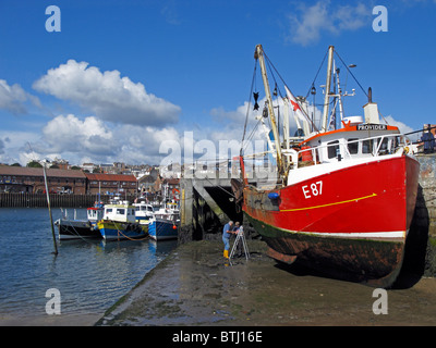 Men working on fishing boat hull, Scarborough harbour Stock Photo