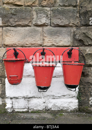 Three red fire buckets on a wall Stock Photo