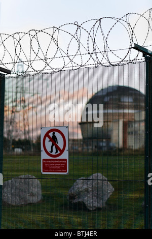 Security fence around the redundant nuclear reactor & reprocessing plant, Sellafield  (focus on fence & sign) Stock Photo