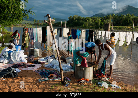 Indian people washing clothes by a flooded river in the town of Puttaparthi, Andhra Pradesh, India Stock Photo