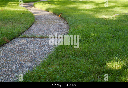 Curved stone and concrete walkway through green grass lawn Stock Photo