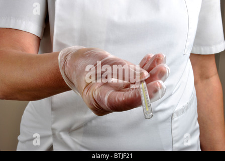 medical staff with disposable gloves gives analogue clinical thermometer Stock Photo