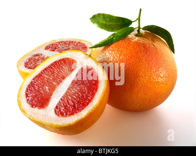 Fresh whole and cut pink grapefruit with leaves against a white background Stock Photo