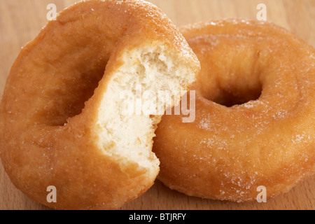 simple plain lightly sugar coated donuts known as gravy rings with bite taken out Stock Photo