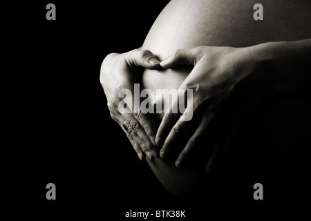 Heart shaped hands on pregnant woman tummy Stock Photo