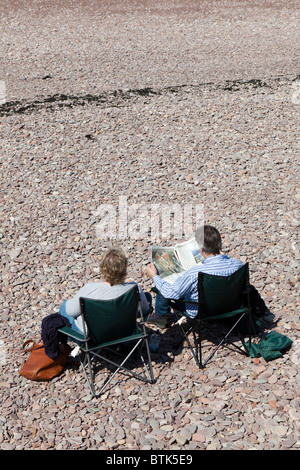 Couple reading on the beach at Watchet, Somerset Stock Photo