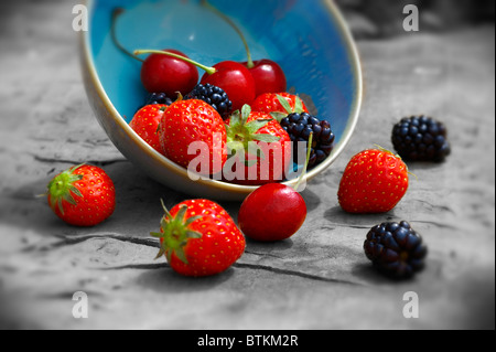 bowl of fresh picked summer soft fruit on a wooden garden table, cherry, strawberry and blackberry Stock Photo
