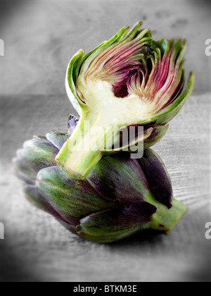 Side shot of Fresh Globe Artichokes (Cynara cardunculus) against a wood background Stock Photo
