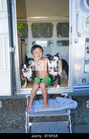 boy sitting in door of camper with dogs Stock Photo