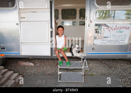 boy and dog sitting in camper doorway Stock Photo